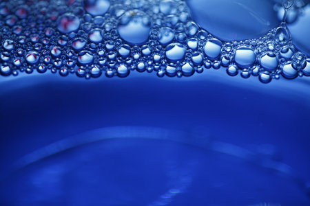 Water drops on the surface of a blue liquid. Abstract background.