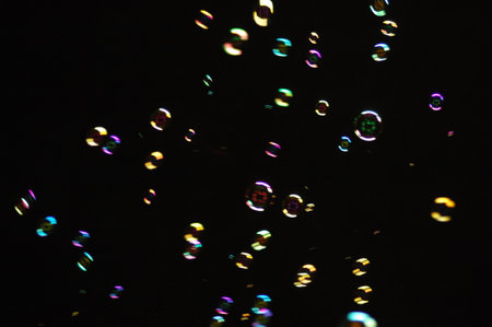 Bokeh of soap bubbles on black background. Blur effect.