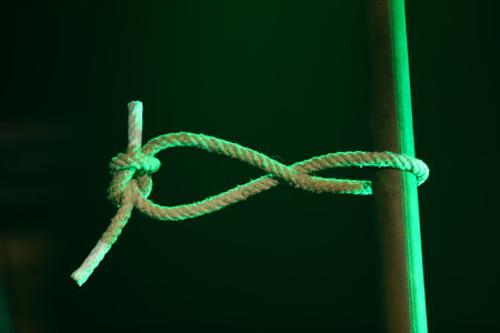 Rope tied with a green cord on a dark green background.の写真素材