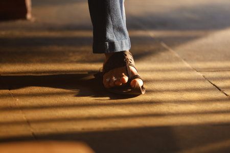 Feet of a man in jeans and shoes on the background of sunlightの写真素材