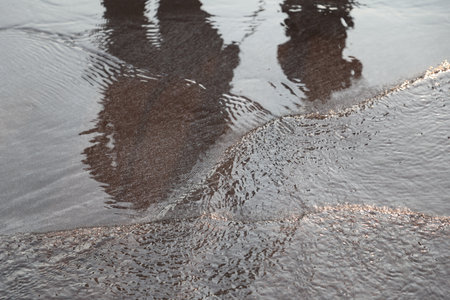 Reflection of a man on the surface of the water in a puddleの写真素材