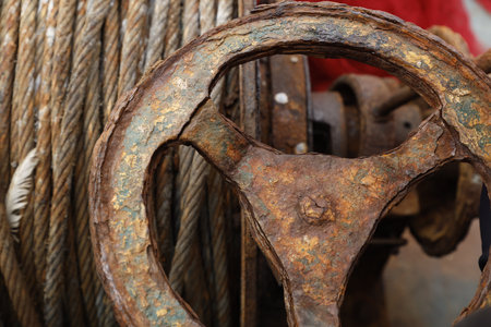 rusty steering wheel and rope in shipyard, closeup of photo