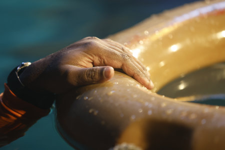 Close up of a male hand holding an inflatable ring in swimming poolの写真素材