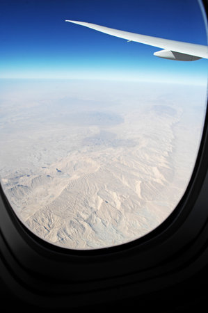 View from the porthole of an airplane flying over the desertの写真素材