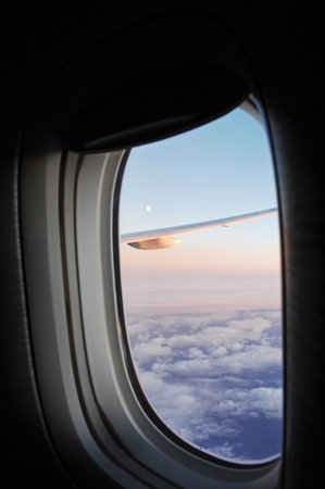 View from airplane window on the clouds and sky through the portholeの写真素材