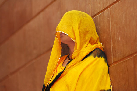 A muslim woman wearing a yellow cloth in front of a wall.の写真素材