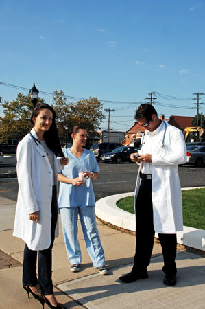 A couple of doctors and a nurse standing in a parking lot.のeditorial素材