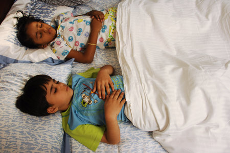 Two little boys lying on the bed and looking at each other.のeditorial素材