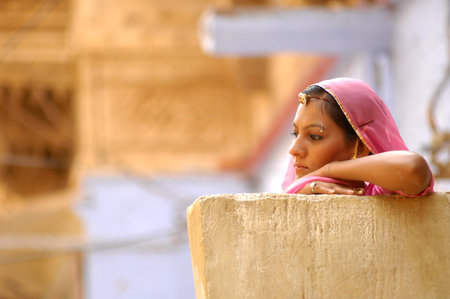 Indian girl in traditional clothes sitting on the wall in Pushkar, Rajasthan, Indiaのeditorial素材