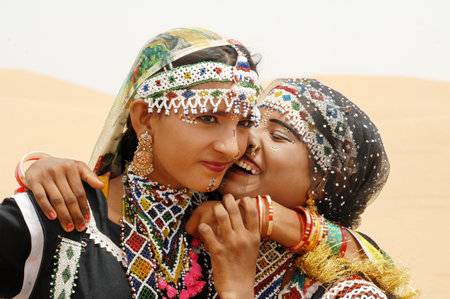 Two women in traditional clothes kissing each other in the middle of the desertのeditorial素材