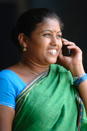 Smiling Indian woman talking on mobile phone in the street, Indiaのeditorial素材