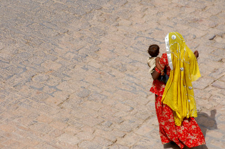 A woman in a yellow dress with a child in her arms.