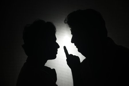 Silhouette of a father and son in a dark room.のeditorial素材