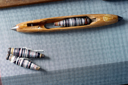 Wooden loom with thread and needles on a gray tablecloth