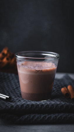 Chocolate milkshake in a glass with cinnamon and anise on dark background