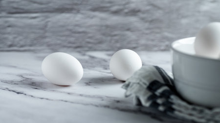 White eggs in a bowl on a white marble table. Copy space.