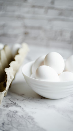 Eggs in a white bowl on a white marble background.