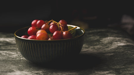 Red berries in a bowl on a dark background. Selective focus.