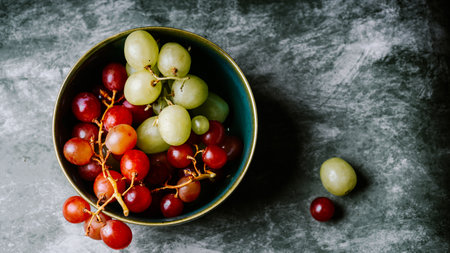 Green and red grapes in a bowl on the table. Top view