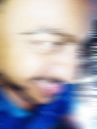An Indian or asian guy showing his funny facial expression to the camera. Blurred or defocused image.の写真素材