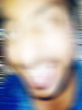 An Indian or asian guy showing his funny facial expression to the camera. Blurred or defocused image.の写真素材