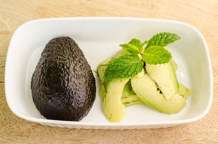Closeup avocado and sliced avocado with mint on top on wooden backgroundの写真素材