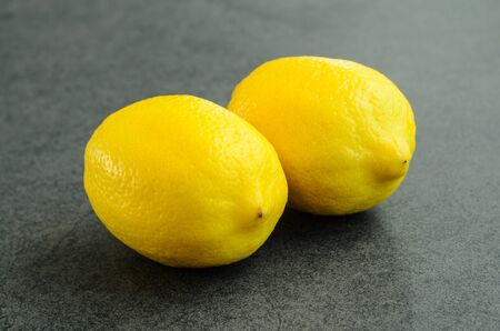 Closeup two whole fresh lemon on stone backgroundの写真素材