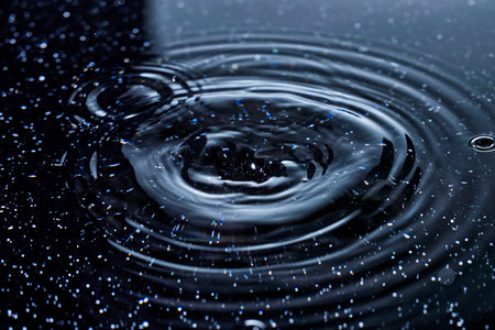 Water drop close-up with ripples on a dark blue backgroundの写真素材