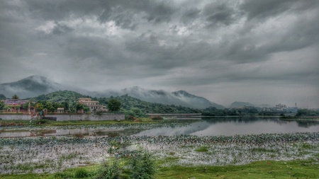 thick dense monsoon clouds covering mountain range having lake in frontの写真素材