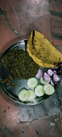 Bowl of sarso ka saag with makki ki roti top view on table