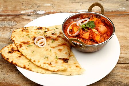 Indian Food or Indian Curry in a copper brass serving bowl with bread or roti.