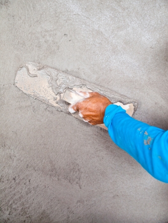 Close-up of hand using trowel to finish wet concrete wallの写真素材