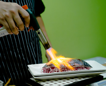 Chef sushi using a torch.の写真素材