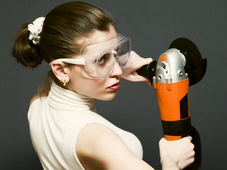 girl in goggles holding angle grinderの写真素材