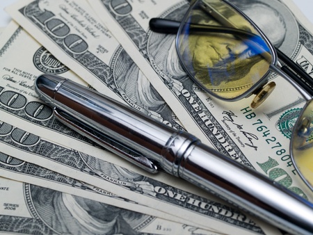 Luxury pen and glasses lie on the dollar billsの写真素材