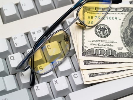 dollar bills and glasses lying on the keyboardの写真素材
