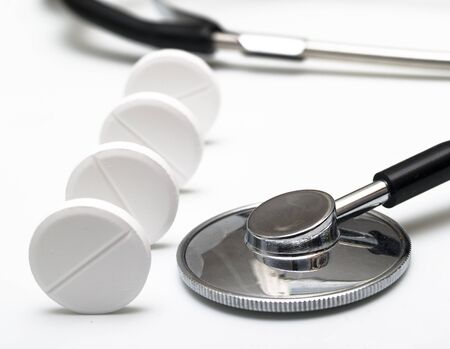 Stethoscope and white tablets on white