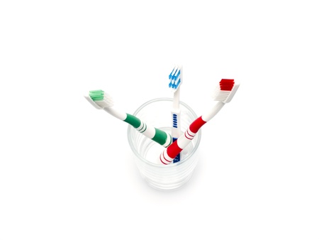 colorful toothbrushes in a glass over white の写真素材