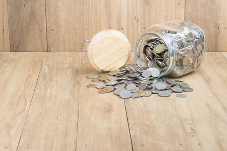 coins in glass bottle on wooden backgroundの写真素材