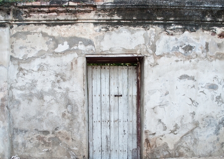Old wooden door is locked on old plaster walls の写真素材