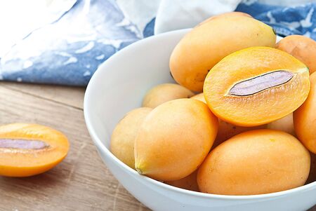 Sweet Marian plum fruit in bowl on wooden background Mayongchid Maprang Marian Plum and Plum...