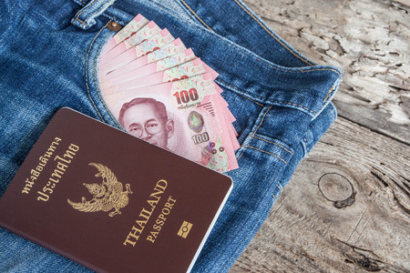thailand passport and thai money banknote in denim jean's pocketの写真素材