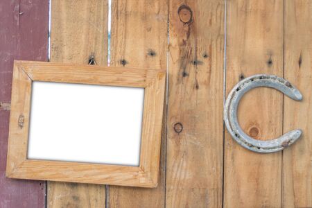 old vintage wooden photo frame and old rusty horseshoe on vintage wooden boardの写真素材