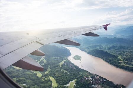 View of beautiful clouds and wing of airplane from window, view of through window aircraft during flight in wing with a nice blue skyの写真素材
