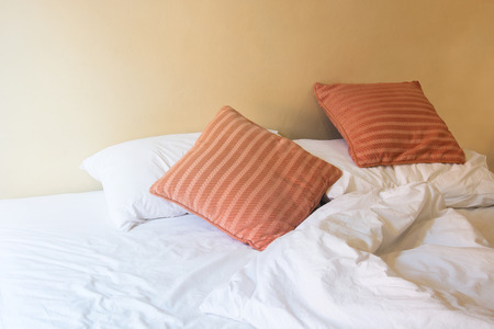 white pillow and orange pillow on bed and with wrinkle messy blanket in vintage bedroom, from...