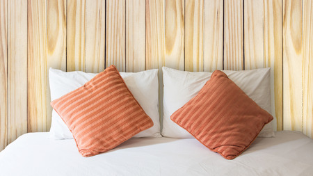 white pillow and orange pillow on bed and with blanket in vintage wooden bedroomの写真素材