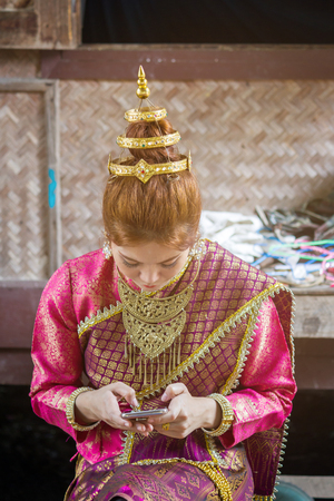 Portrait asian woman wearing traditional Laos take the telephone, beautiful Laos woman in Laos costume, beautiful asian woman take the technologyの写真素材