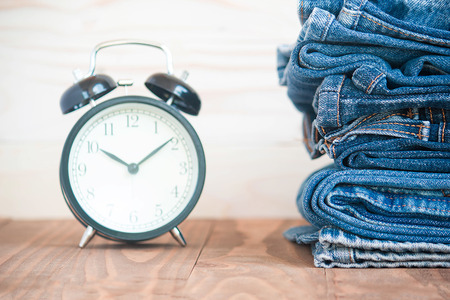Stack Of Jeans And Classic Timepieces On Old Wood Flooring,Fashion Concept With Timeの写真素材
