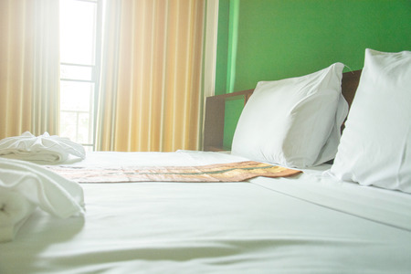 White pillows and white towels on bed in green wall roomの写真素材