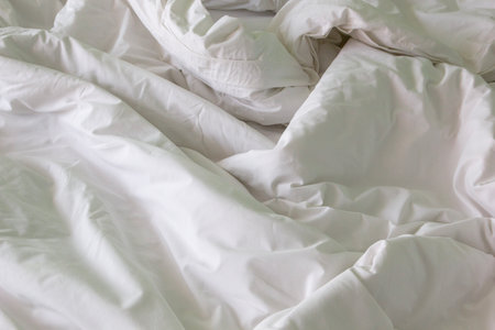 wrinkled blanket and duvet with natural folds and texture, showing white bedding detailsの写真素材